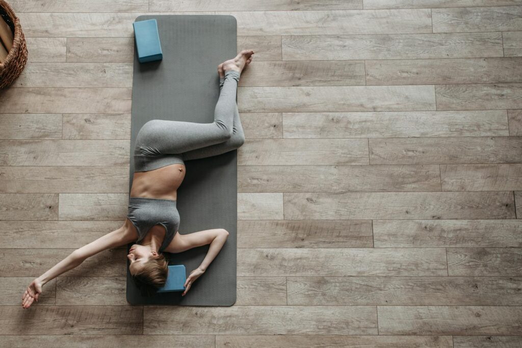 Pregnant woman performing yoga exercise indoors on a mat for health and relaxation.